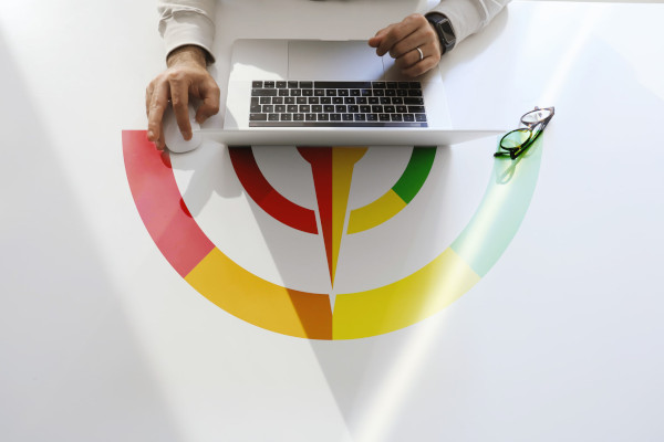 Person using a laptop on a table featuring a traffic light scoring barometer.